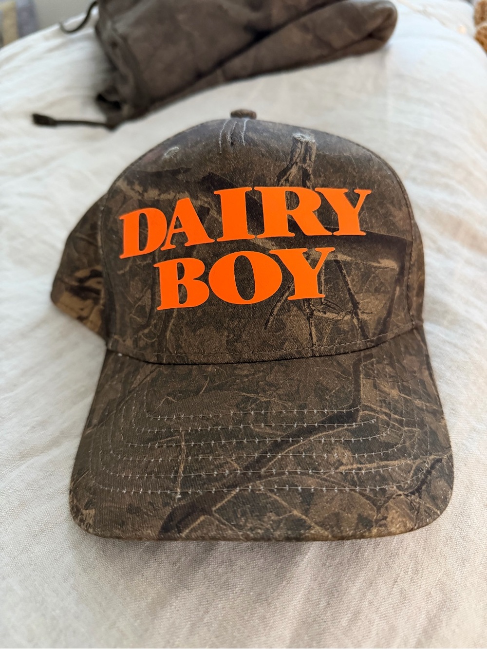 Dairy Boy Camouflage Baseball Cap in Orange Text